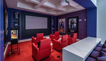 A theater room with red chairs and a projector screen